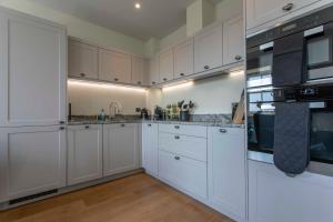 uma grande cozinha branca com armários e electrodomésticos brancos em Beautiful, modern apartment in Hope Place Bath, 1 Bedroom Luxury City Centre Apartment with Beautiful City Views, a stones throw from The Royal Crescent in Bath em Bath