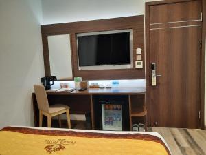 a hotel room with a desk with a tv and a bed at Prague Saigon Airport Hotel in Ho Chi Minh City