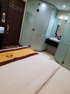 1 dormitorio con 1 cama blanca grande y baño en Prague Saigon Airport Hotel, en Ho Chi Minh