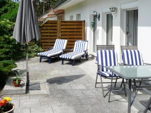 trzy krzesła, stół i parasol na patio w obiekcie Holiday Home Am Walde by Interhome w mieście Lubmin