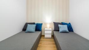 2 łóżka w pokoju z niebieskimi poduszkami w obiekcie Baltic Capital - BillBerry Apartments w Gdańsku