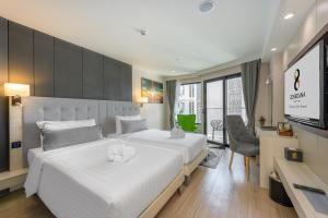 a bedroom with a large white bed and a television at Zenseana Resort & Spa - SHA Plus in Patong Beach