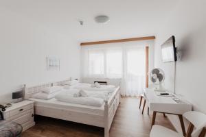 a white bedroom with a large white bed and a desk at Hotel Mörbischerhof in Mörbisch am See