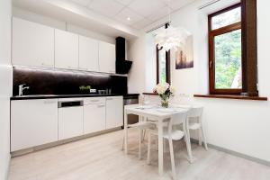 a kitchen with white cabinets and a white table and chairs at Apartments Daina in Jūrmala