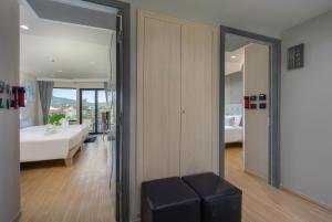 a room with a bedroom with a bed and a stool at Zenseana Resort & Spa - Patong, Phuket in Patong Beach