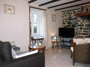 ein Wohnzimmer mit einem Sofa und einem TV in der Unterkunft Holiday Home La Chevalerie - SUB102 by Interhome in Sourdeval-les-Bois