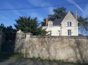 une maison blanche derrière un mur en pierre dans l'établissement Le Clos Des Ormeaux, à Vineuil