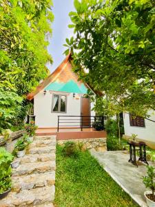 a small white house with a green roof at Tropical Valley Homestay in Phong Nha