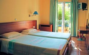 a hotel room with two beds and a balcony at Poseidon Apartments in Agios Gordios