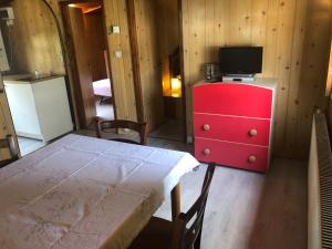 FaedisにあるElenas cottageのテーブルとテレビ付きの赤いドレッサーが備わる客室です。