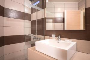 a bathroom with a white sink and a glass shower at Atrion Resort Hotel in Agia Marina Nea Kydonias