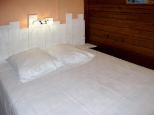 a white bed in a room with a wooden wall at Holiday Home Tramariccia-3 by Interhome in Calvi
