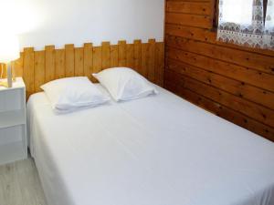 a bedroom with a white bed with a wooden headboard at Holiday Home Tramariccia-3 by Interhome in Calvi