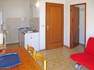 una pequeña cocina con mesa y silla roja en Apartment Thalassa - CAL200 by Interhome, en Calvi