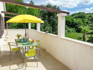 a patio with a table and yellow chairs and an umbrella at Holiday Home Palma - MVN202 by Interhome in Karojba