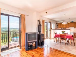 a living room with a television and a table with chairs at Holiday Home Kušar by Interhome in Motovun