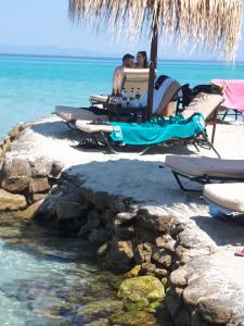 two people sitting on the beach under an umbrella at George apartments in Kallithea Halkidikis