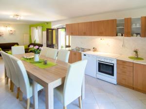 a kitchen with a wooden table and white chairs at Holiday Home Sara - PRC136 by Interhome in Poreč