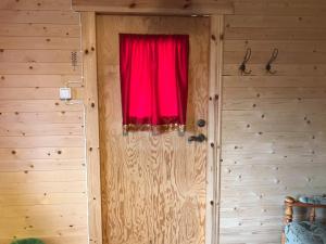 a red window in a room with a wooden wall at Stuga in Romakloster
