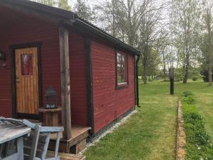 a red cabin with a porch and a door at Stuga in Romakloster