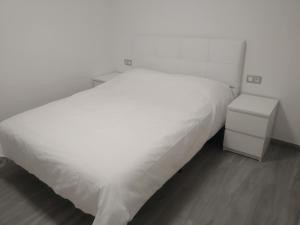 a bedroom with a white bed and a night stand at Jandia Suite in Morro del Jable