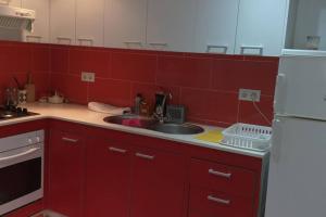 uma cozinha vermelha com um lavatório e um frigorífico em Apartamento vacaciones em Palafrugell