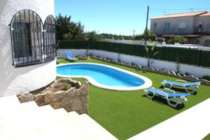 a backyard with a swimming pool and chairs and a fence at Villa Paradis in Miami Platja