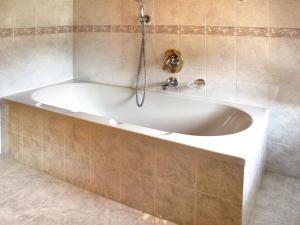 a white bath tub in a tiled bathroom at Apartment Giuditta by Interhome in Pera