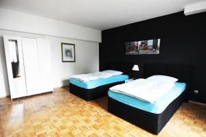 2 Betten in einem Zimmer mit schwarzen Wänden und Holzböden in der Unterkunft Dorya am Ring in Köln