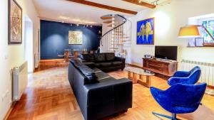 sala de estar con sofá negro y sillas azules en Villa Oria, en Pula
