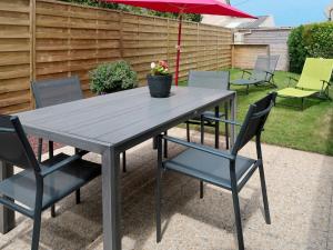 a picnic table with chairs and an umbrella at Holiday Home Tal Ar Mor - PLC213 by Interhome in Plounévez-Lochrist