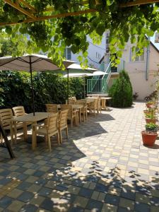 a patio with tables and chairs and umbrellas at Guest House Vinogradnaya 4 in Anapa