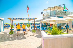 twee mannen in gele shirts lopen op het strand bij Hotel Ambasciatori in Bellaria-Igea Marina