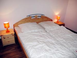 ヒンメルプフォルトにあるHoliday Home Waldhäuser-1 by Interhomeのベッド(白いシーツ、ナイトスタンドのランプ2つ付)