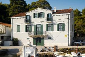 a large white house with green shutters and a boat at Private luxury Villa del Mar on Solta for up to 10 persons, heated pool, free parking, next to sea! FREE Kajak & Mountainbikes, GREAT living area & privacy! in Rogač