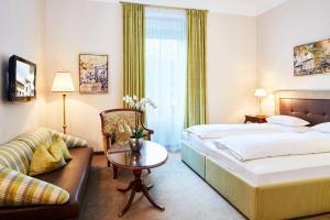 a hotel room with a bed and a table and a couch at Parkhotel Graz - Traditional Luxury in Graz