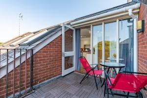 a patio with red chairs and a table on a deck at Beautiful Flat Town Centre 55 inch Smart TV + Netflix in Andover