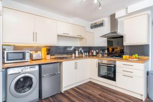 a kitchen with white cabinets and a washer and dryer at Beautiful Flat Town Centre 55 inch Smart TV + Netflix in Andover