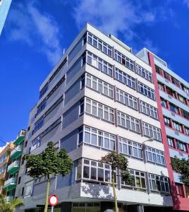 ein hohes weißes Gebäude mit Bäumen davor in der Unterkunft Sweet Home Las Canteras in Las Palmas de Gran Canaria