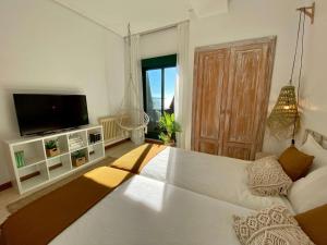 uma grande cama branca num quarto com uma televisão em Samil55 em Vigo