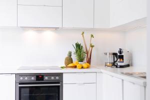 a kitchen with white cabinets and fruits on the counter at Smile Apartments zum Goldenen Hirschen in Krems an der Donau