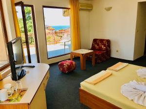 a room with two beds and a chair and a window at Family Hotel Friends in Primorsko