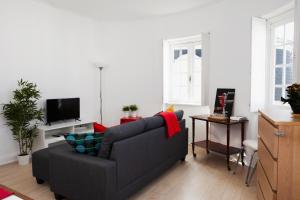 ein Wohnzimmer mit einem Sofa und einem TV in der Unterkunft Avenida Central Viana - City and River Apartment in Viana do Castelo