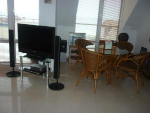 a living room with a television and a table with chairs at Апартмент Blue Sky in Sveti Vlas
