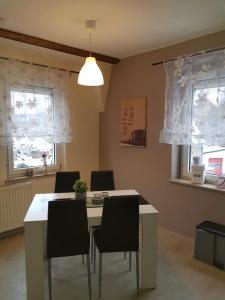 comedor con mesa, sillas y 2 ventanas en Ferienwohnung Alina, Limbach-Oberfrohna en Limbach - Oberfrohna