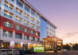 un gran edificio con coches estacionados en un estacionamiento en CBD 2 Hotel en Surat Thani