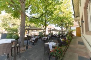 un patio al aire libre con mesas, sillas y árboles en Hotel Landgasthof Riehen / Basel, en Basilea