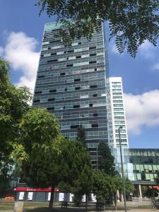 a tall glass building with trees in front of it at Sotell Apartment Gran Via Europa BCN in Las Corts
