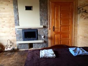 a room with a stone fireplace and a bed and a door at Садиба над потічком in Oriv