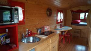 una cocina con fregadero en una cabaña de madera en La Girardière, en Le Boupère